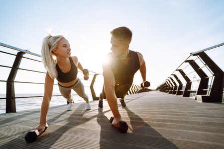 Romantic couple doing sport together at the beach pier. Two sporty athletes doing warming-up exercises.の写真素材