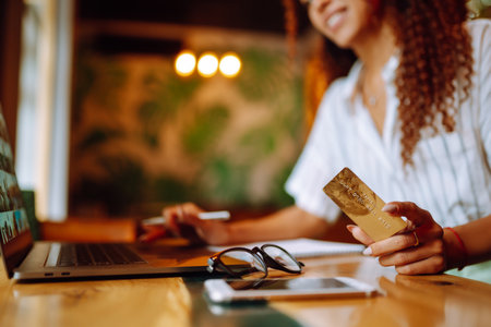 Young woman sitting at cafe making online shopping, using credit card and laptop. online shoppingの写真素材