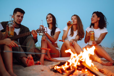 Group of happy friends cheers and drink beers on the beach, enjoying vacation. vacation time laughing.の写真素材