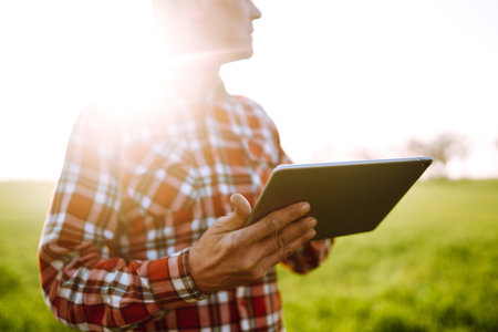 Farmer on a green wheat field with a tablet in his hands. Farmer checking his crops on an agricultural.の写真素材