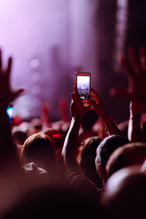 Hand with a phone records live music festival. People taking photographs with smart phones.の写真素材