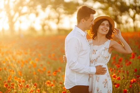 Loving couple in the poppy field at sunset. enjoying time together. love and lifestyle.の写真素材