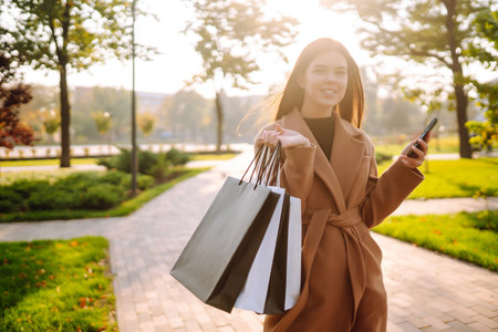 Smiling woman with shopping bags walking down the street. Purchases, black friday, discountsの写真素材