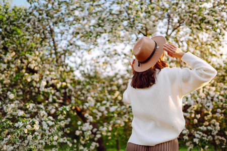 Smiling woman with hat posing in blooming spring park. The concept of relax, travel. fashion style.の写真素材