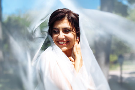 A beautiful portrait of the bride under a veil. Elegant woman with professional make up and hair style.の写真素材