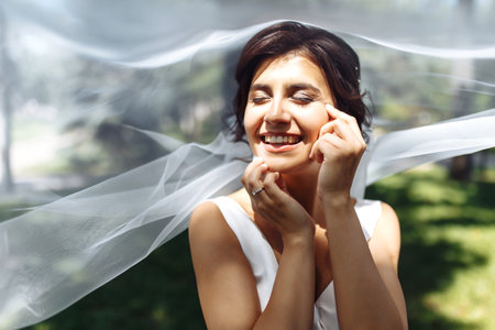 A beautiful portrait of the bride under a veil. Elegant woman with professional make up and hair style.の写真素材