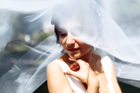 A beautiful portrait of the bride under a veil. Elegant woman with professional make up and hair style.の写真素材