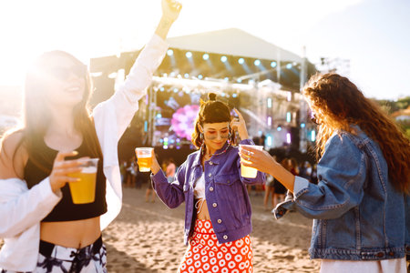 Girlfriends drinking beer, having fun at music festival. friendship and celebration. summer holiday.の写真素材