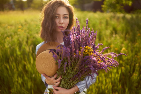 Portrait of a beautiful girl with a bouquet of lavender. Sunset light and beautiful sensuality.の写真素材