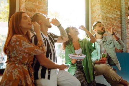 Happy friends having a great time in cafe. Young people sitting in a restaurant having fun togetherの写真素材