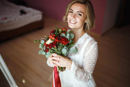 Beautiful bride with wedding flowers bouquet in white luxury dress is getting ready for wedding.の写真素材