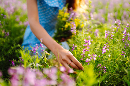 Young woman in stylish summer dress feeling free in the field with flowers in sunshine. summer landscapeの写真素材