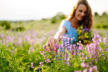 Young woman in stylish summer dress feeling free in the field with flowers in sunshine. summer landscapeの写真素材