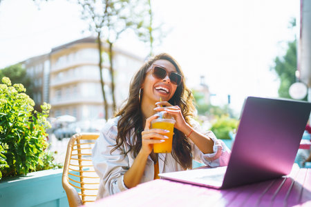 Portrait of a happy young woman with a laptop at cafe. Freelancer working on a laptop. business onlineの写真素材