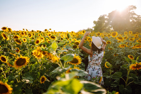 Young woman walks on blooming sunflower field. Happiness with nature.. Summer holidays.の写真素材