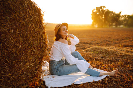 Happy woman near haystack at sunset. fashion concept. Nature, vacation, relax and lifestyle.の写真素材