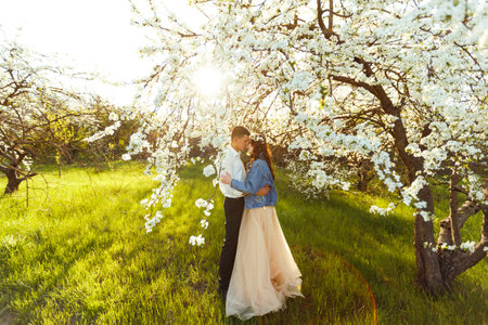 Beautiful loving couple in blooming gardens. wedding concept. Great sunset light. Lovely newlyweds.の写真素材
