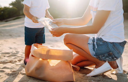 Child with mother collects plastic, garbage on the beach by sea. Empty used dirty plastic bottles.の写真素材