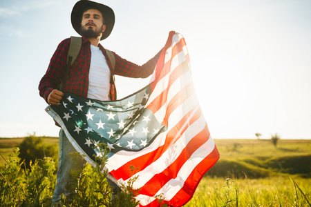 4th of July. american flag. Traveler with the flag of America. The man in a hat, a backpack, a shirt and jeans.の写真素材