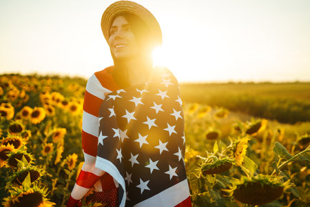 Beautiful girl in hat with the American flag in a sunflower field. 4th of July. Fourth of July. independence day.の写真素材