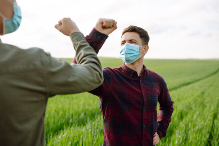 Two Farmers in protection mask with tablet in the field. Modern agriculture technology.Smart farmingの写真素材