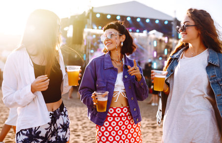 Girlfriends drinking beer and having fun at music festival. friendship and celebration. beach party.の写真素材