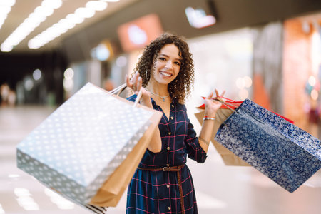 Smiling woman with shopping bags enjoying shopping in the mall.Young woman with packages after shopping.の写真素材