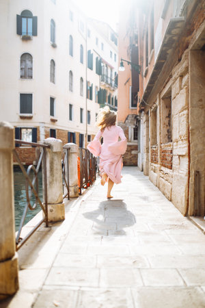 Portrait of stylish woman in pink dress, walks through sunny streets of Venice. travel concept.の写真素材