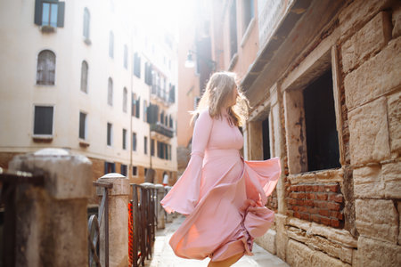 Portrait of stylish woman in pink dress, walks through sunny streets of Venice. travel concept.の写真素材