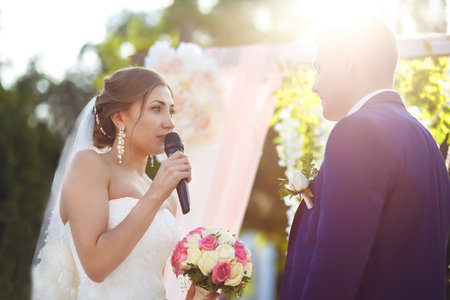 Happy groom and beautiful bride at a wedding ceremony under the arch decorated with flowers.の写真素材
