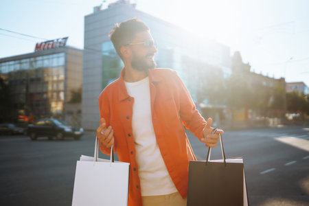 Fashion man with shopping bags walking on the street. Consumerism, sale, purchases, shopping.の写真素材