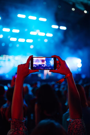 Hand with a phone records live music festival. People taking photographs with smart phones.の写真素材