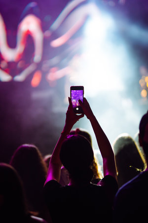 Hand with a phone records live music festival. People taking photographs with smart phones.の写真素材