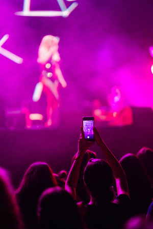 Hand with a phone records live music festival. People taking photographs with smart phones.の写真素材