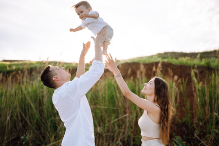 Cheerful young family with little baby boy spending time together on the beach.