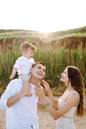 Cheerful young family with little baby boy spending time together on the beach.の写真素材