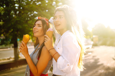 Two young female friends having fun and eating ice cream. Young women enjoy summer and vacation.の写真素材