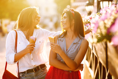 Two young female friends having fun and eating ice cream. Young women enjoy summer and vacation.の写真素材