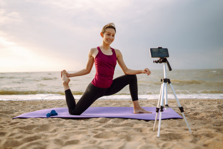 Online training. Sporty woman yoga coach records video online training yoga on the beach. sport.の写真素材