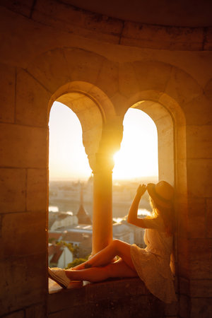 Young female tourist enjoys the view of the city at sunset. Travel and tourism concept.の写真素材