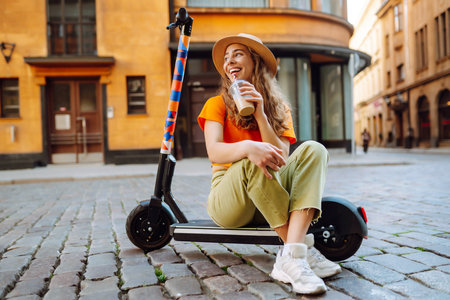 Woman on vacation having fun driving electric scooter through city. Ecological transport concept.の写真素材