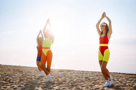 Beautiful women in swimsuits are dancing on the beach. Fitness, training, aerobics and people concept.の写真素材