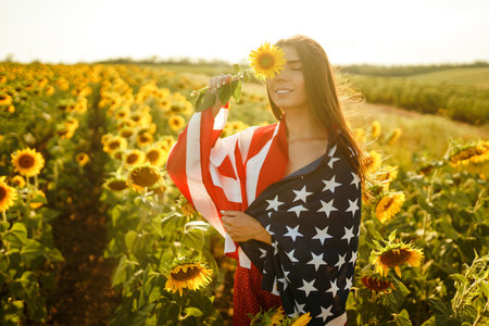 Beautiful girl in hat with the American flag in a sunflower field. 4th of July. Fourth of July....