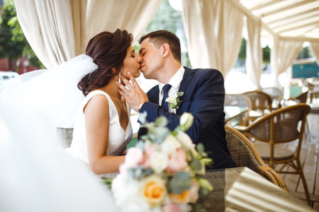 Young bride and groom in a cafe. Husband and wife hold each other's hands. Loving couple in a restaurant.の写真素材