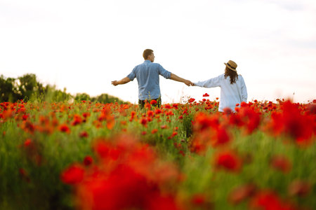 Loving couple walking on the poppy field. enjoying time together. The concept of youth, love and...
