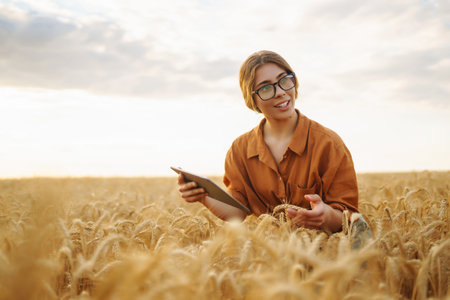 Farmer woman in a wheat field touches the ears of barley. Rich harvest concept.