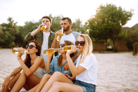 Group of friends cheers and drink beers on the beach. Young friends relaxing and having a picnic. Susummertime.の写真素材