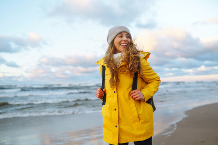 The girl tourist in a yellow jacket posing by the sea. Traveling, lifestyle, adventure.の写真素材