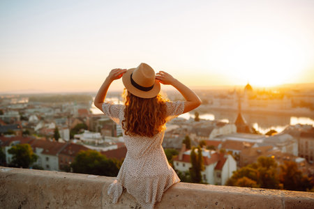 Young female tourist looking at panoramic view of the city at sunset. Lifestyle, travel, active lifeの写真素材