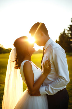Lovely wedding couple at sunset. Bride, groom in wedding attire with bouquet of flowers. Romantic.の写真素材